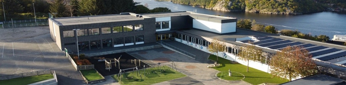 Dronebilde av Farsund barneskole etter nybygget stod ferdig. I bakgrunnen kan man se fjorden. - Klikk for stort bilde