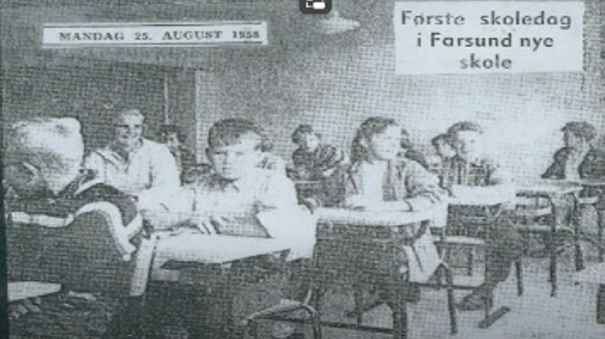 Gammelt skolefoto fra første skoledag inne i et av klasserommene, hvor elever sitter ved pultene sine. - Klikk for stort bilde